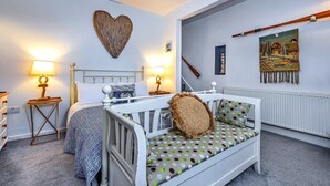 Une chambre à coucher avec un lit, des tables de chevet, un décor mural en forme de cœur, un tableau et un instrument de musique en bois.