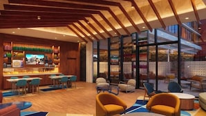 Un intérieur moderne avec un bar, des espaces aménagés pour s’asseoir et de grandes fenêtres.