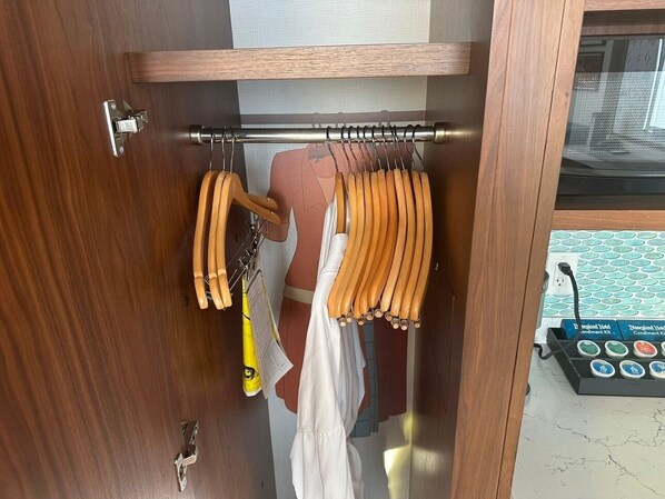 Une armoire en bois avec une tringle pour suspendre les vêtements et un miroir.