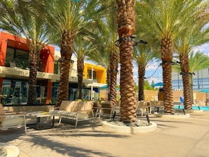 A courtyard with palm trees, outdoor seating, and a pool area.