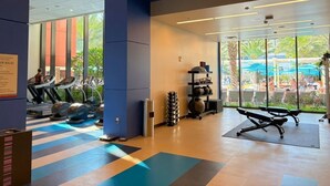 Une salle de sport équipée de tapis de course, de ballons d’exercice et d’un banc.