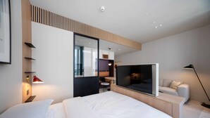 Ett modernt hotellrum med en stor säng, en TV, ett skrivbord och en sittgrupp.