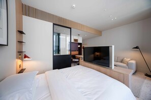 A modern hotel room with a large bed, a TV, a desk, and a seating area. - Prime Business Bay Studio | Burj View (Dubai)