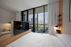A modern hotel room with a large bed, a TV, a balcony with a city view, and a desk with a lamp. - Prime Business Bay Studio | Burj View (Dubai)