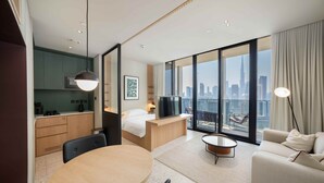 Una moderna camera d'albergo con angolo ristoro, un letto, una TV e vista sulla città.