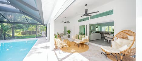 A modern indoor pool area with a glass ceiling, wicker furniture, and a view of the outdoors.