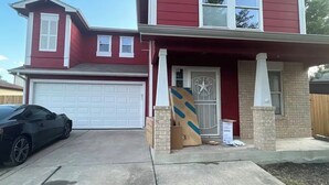 Une maison à deux étages avec un garage, une allée et une voiture garée.