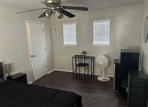 A bedroom with a bed, a ceiling fan, a desk, a chair, a small table, a fan, and a dresser. - Private bedroom in house near COTA and Tesla (Austin)