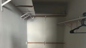 Un couloir étroit doté d’un plancher sombre, de murs blancs et d’un plafond avec des poutres apparentes.
