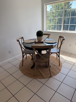 A dining area with a round table, four chairs, a potted plant, and a window with a view of trees. - 3-bedroom townhome in lovely White Salmon with AC (White Salmon)