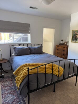 A bedroom with a bed, a dresser, a window, and a door. - 3-bedroom townhome in lovely White Salmon with AC (White Salmon)
