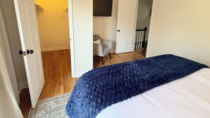 Une chambre à coucher comprenant un lit, une chaise et une porte donnant sur une salle de bain.