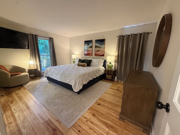 Un dormitorio con cama, una silla, un televisor y un armario de madera.