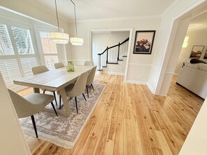 A dining area with a wooden table and chairs, a patterned rug, and a staircase leading to another level. - 3-bedroom townhome in pleasant Charlotte with AC and charm (Charlotte)