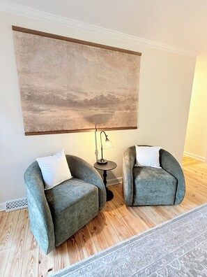 A room with two armchairs, a large abstract painting, a floor lamp, and a patterned rug. - 3-bedroom townhome in pleasant Charlotte with AC and charm (Charlotte)