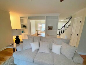 A living room with a sectional sofa, a lamp, a staircase, and a door leading to another room. - 3-bedroom townhome in pleasant Charlotte with AC and charm (Charlotte)