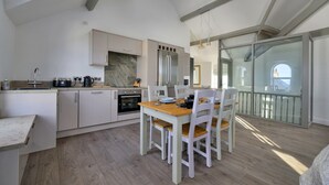 Eine moderne Küche mit Essbereich, Holzboden und Blick ins Freie.