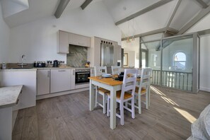 Eine moderne Küche mit Essbereich, Holzboden und Blick ins Freie.
