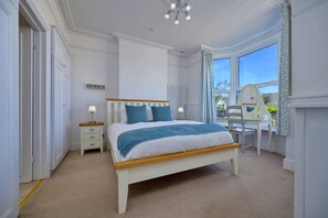 Une chambre à coucher comprenant un lit, des tables de chevet, un bureau et une chaise.