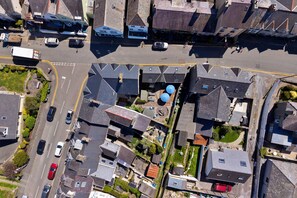 Vue aérienne d’un quartier résidentiel avec des maisons, une route et des voitures garées.