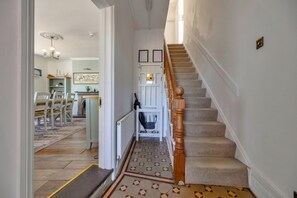 Un escalier avec une rampe en bois et des marches recouvertes de moquette, menant à un palier où se trouve une porte blanche.