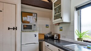 A compact kitchen with a microwave, toaster, and a small window with a plant. - Luxury Cornish Countryside Hut for 2 (Bude)