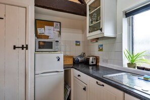 Eine kleine Küche mit Mikrowelle, Toaster und einem Fenster mit Pflanze.