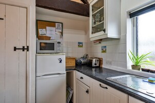 Una cocina compacta con microondas, tostadora y una pequeña ventana con una planta.