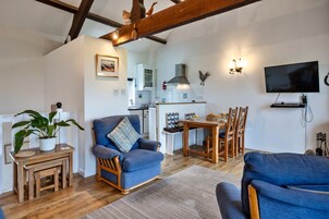Una sala de estar acogedora con un sillón azul, una mesa de centro de madera y un comedor con mesa y sillas.