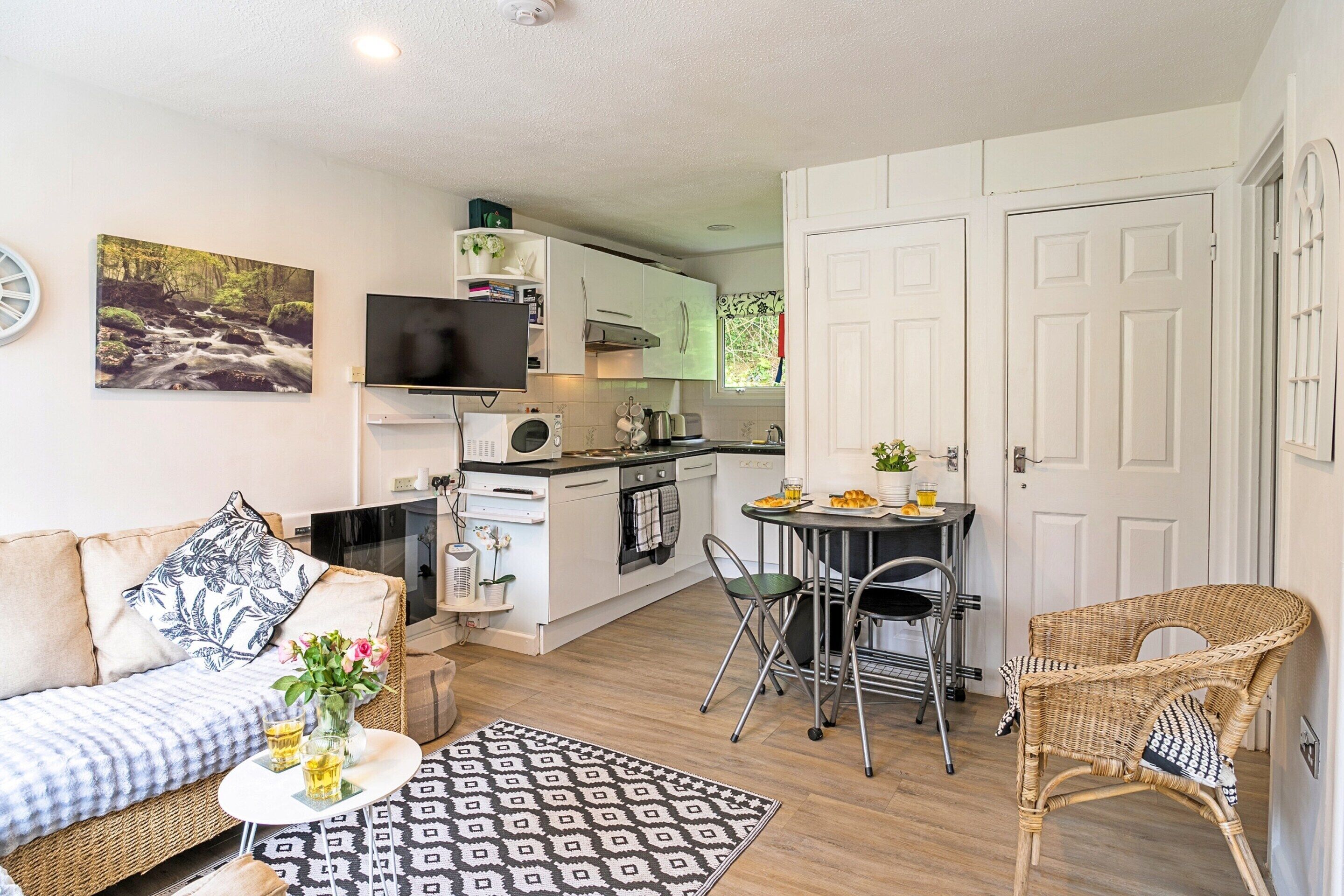 A compact living space with a kitchenette, a dining area, and a seating area with a sofa and chairs.