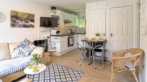 Um espaço compacto com cozinha compacta, área de jantar e sala de estar com sofá e cadeiras.