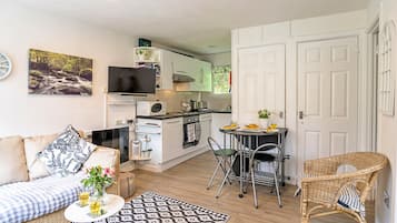 A compact living space with a kitchenette, a dining area, and a seating area with a sofa and chairs.