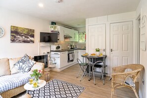 A compact living space with a kitchenette, a dining area, and a seating area with a sofa and chairs. - Camelford Base Near Beaches (Camelford)
