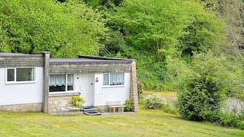 A two-story house with a stone facade, a front porch with a bench, and a small garden area.