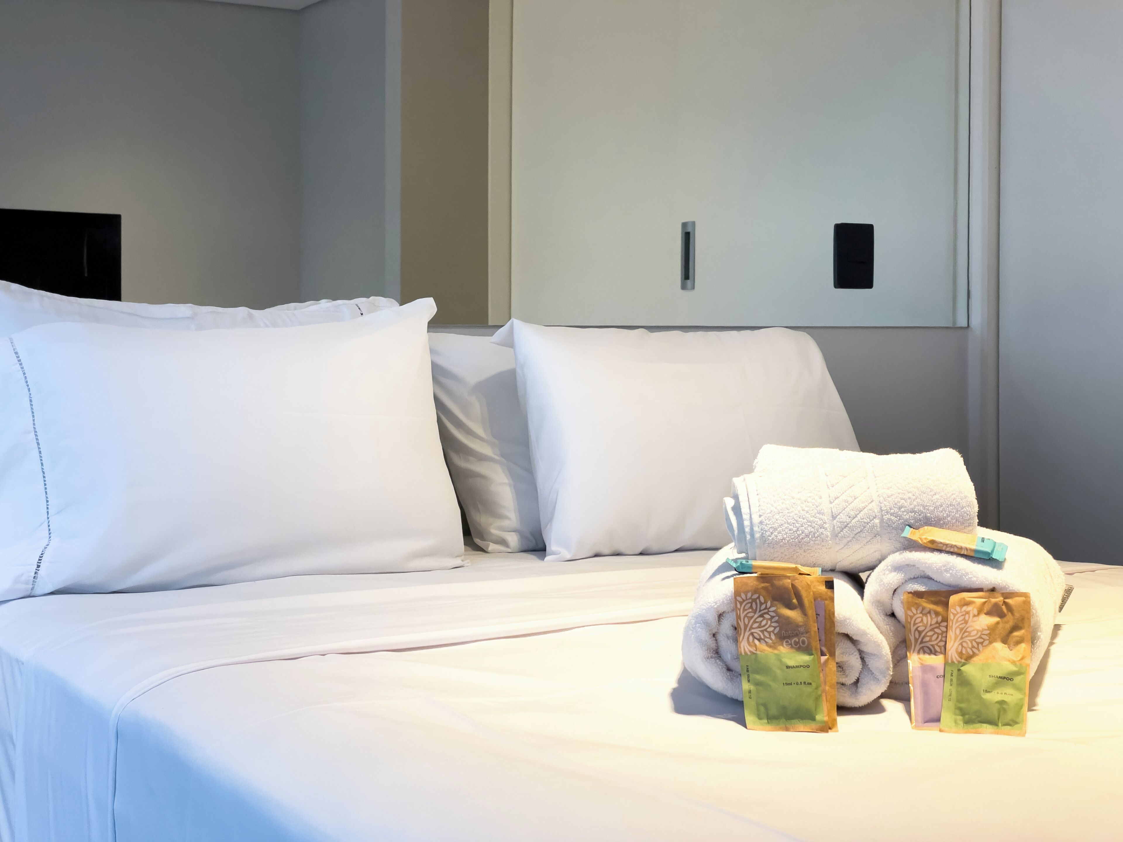Una habitación de hotel con una cama bien hecha, almohadas y artículos de aseo.