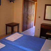 Un dormitorio con cama, armario, una mesita y espejo.
