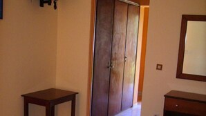Een hotelkamer met twee bedden, een tafeltje, een televisie en een kledingkast.