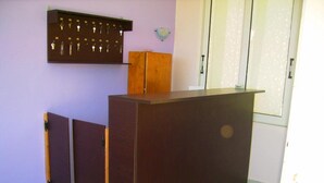 Een receptiebalie met een houten afwerking, een sleutelrek aan de muur en een deur met een geëtste glazen panelen.