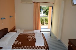 A hotel room with a bed, a wooden headboard, a small bedside table, and a view of the outside.