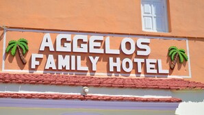 Een bord voor Hotel Agge-los Family, versierd met palmbladeren.