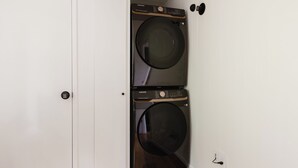 Uma lavanderia com duas máquinas de lavar empilhadas e uma porta com fechadura.
