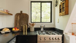 Uma cozinha com fogão a gás, forno e janela com vista para árvores.