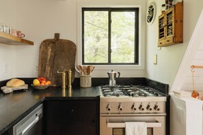Eine Küche mit Gasherd, Backofen und einem Fenster mit Blick auf Bäume.