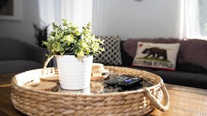 Ein gewebter Tablett mit einem Blumentopf und Fernbedienungen auf einem Holztisch.