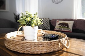 Ein gewebter Tablett mit einem Blumentopf und Fernbedienungen auf einem Holztisch.