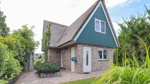 A single-story house with a brick exterior, a thatched roof, and a small front porch. - Waterfront Beach Villa for 5 (Makkum)