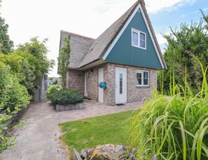 A single-story house with a brick exterior, a thatched roof, and a small front porch. - Waterfront Beach Villa for 5 (Makkum)