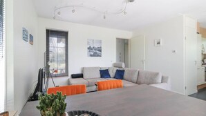A modern living room with a sofa, a dining table, and a potted plant. - Waterfront Beach Villa for 5 (Makkum)