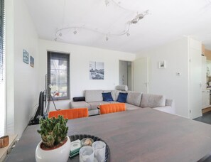 A modern living room with a sofa, a dining table, and a potted plant. - Waterfront Beach Villa for 5 (Makkum)