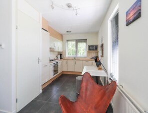 A compact kitchen with white cabinets, a microwave, and a window with blinds. - Waterfront Beach Villa for 5 (Makkum)